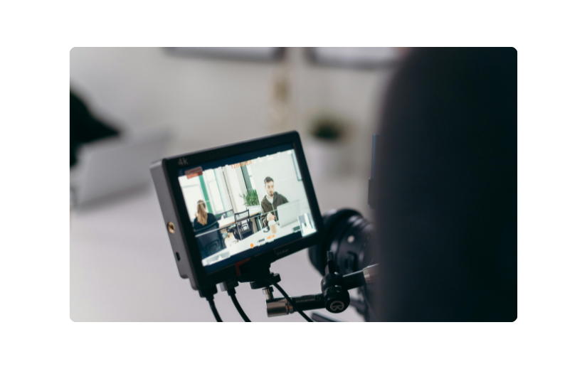 Behind the scenes of an eCommerce video production showing a camera filming two people working in an office.